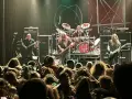 Concert de metal, musiciens sur scène, foule en délire. Le groupe semble prêt à envoyer du lourd, un vrai voyage ad patres pour les fans.