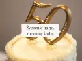 Złote cyfry "50" na torcie z kremem, ozdobione kryształkami. Napis: "Życzenia na 50. rocznicę ślubu".