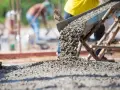 Beton wylewany z betoniarki. Pracownicy na budowie, zastanawiają się, ile cementu na kubik betonu potrzeba do wykonania solidnej konstrukcji.