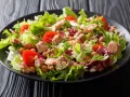 Ein frischer Thunfischsalat mit knackigem Salat, Tomaten und Bohnen auf einem schwarzen Teller.