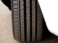 Primo piano del battistrada gomme di un'auto bianca, con solchi profondi per una presa ottimale sull'asfalto.