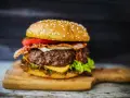 Soczysty burger z bekonem, serem i warzywami na desce.