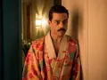 Freddie Mercury w barwnym szlafroku, jakby zrodzony z **bohemian rhapsody**, opiera się o drzwi.