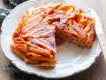 Una deliziosa frittata di pasta, dorata e croccante, servita su un piatto bianco con un coltello.
