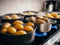 Flera kastruller med potatis som får koka på spisen. Ånga stiger upp från det bubblande vattnet.