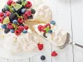 Beza pavlova która zawsze wychodzi, udekorowana świeżymi malinami, borówkami, jeżynami i plasterkami limonki.
