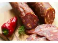 Kawałki pikantnego chorizo, czerwona papryczka i natka pietruszki na desce. Dowiedz się, chorizo co to jest!