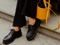 Come abbinare le stringate femminili: look audace con pantaloni neri e borsa gialla.
