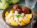 Klassische Kohlrabi-Rezepte: Kohlrabi in cremiger Sauce mit Kartoffeln und Frikadellen, garniert mit Petersilie.
