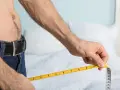 Mężczyzna mierzy obwód talii, zastanawiając się, kiedy rośnie prącie.