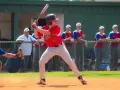 Młody zawodnik w czerwonej koszulce z numerem 5 przygotowuje się do odbicia piłki. Czy to softball? Tak, to gra zespołowa, podobna do baseballu.