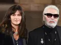 Karl Lagerfeld, iconico stilista Chanel, con una donna dai capelli scuri e un sorriso discreto.