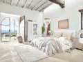 Elegantes dormitorio ideas con cama grande, armario blanco y puertas abiertas a un paisaje soleado.
