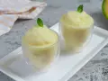 Dos copas de refrescante sorbete de melón, decoradas con hojas de menta, listas para disfrutar en un día caluroso.