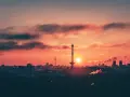 Berlin bei Nacht von oben: Die Sonne geht unter und taucht den Himmel in ein feuriges Rot. Silhouetten von Türmen und Gebäuden zeichnen sich ab.