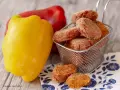 Polpette di peperoni dorate e croccanti, servite in un cestino, accanto a peperoni freschi rossi e gialli.