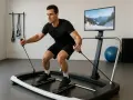 Mężczyzna ćwiczy na symulatorze narciarskim, który przypomina spinning. Ekran pokazuje zimowy krajobraz.
