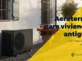 Unidad exterior de bomba de calor aire-agua junto a una casa antigua con flores. Aerotermia para viviendas antiguas.