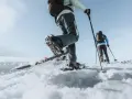 Deux personnes font une randonnée hivernale en raquettes sur un paysage enneigé sous un ciel bleu clair.