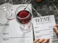 Ręka zapisuje notatki z degustacji wina. Kieliszki z czerwonym winem i arkusz "Wine Tasting" sugerują, jak degustować wino.