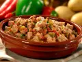 Un plat d'axoa de veau mijoté avec des poivrons et des oignons, garni de persil frais.