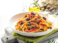 Un piatto invitante di spaghetti alla puttanesca, con olive nere, capperi e pomodoro, pronto per essere gustato.