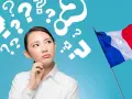 Mujer pensativa rodeada de signos de interrogación, con la bandera francesa ondeando. ¿Qué tipos de francés aprenderá?