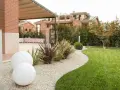 Giardino moderno con ghiaia bianca, sfere luminose e piante decorative. Belle idee giardino ingresso casa per un'accoglienza elegante.