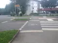Ein Zebrastreifen mit Fahrradsymbolen auf dem Asphalt. Ein Schild weist in alle Richtungen.