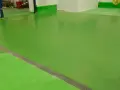 Un impecable pavimento industrial verde brillante, con una rejilla metálica a lo largo de una sección.