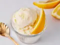 Erfrischendes Zitroneneis selber machen: Cremiges Eis im Glas mit Zitronenspalte und goldener Löffel.
