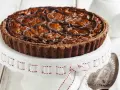 Deliziosa crostata al cioccolato con noci pecan caramellate e un elegante motivo di cioccolato fuso. Perfetta per ogni occasione.