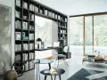 Libreria a muro con scrivania integrata, perfetta per idee stanza studio piccola. Sedia azzurra, tavolini neri e vista piscina.