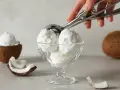 Copa de cremoso helado de coco, con trozos de coco fresco alrededor. ¡Un postre tropical!