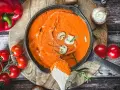 Cremige Metaxa-Sauce in einer Gusseisenpfanne, garniert mit Pilzen und Rosmarin. Daneben rote Paprika und Kirschtomaten.