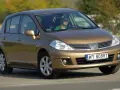 Złoty Nissan Tiida z mężczyzną za kierownicą jedzie po drodze.