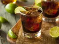 Orzeźwiający drink z rumem Bacardi, lodem i limonką na drewnianej desce.
