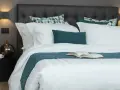 Letto con trapunta bianca a righe, cuscini coordinati e un libro aperto. Ecco come mettere la trapunta nel letto per un riposo perfetto.