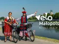 Para w strojach ludowych na rowerach nad Wisłą, promuje Velo Małopolska.