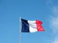 Die französische Flagge weht im Wind vor blauem Himmel. Ein Symbol für ein spannendes Auslandsjahr in Frankreich.