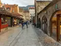 Spacerem po urokliwej uliczce w Sarajewie, gdzie widać sklepy i ludzi. Czy w Sarajewie jest bezpiecznie? Tak, spacerowicze czują się swobodnie.