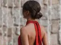 Elegante moño bajo en una mujer con vestido rojo, luciendo su espalda descubierta y un pendiente llamativo.