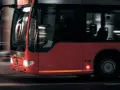 Czerwony autobus w ruchu miejskim, widok z przodu i z boku.