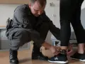 Funkcjonariusz zakłada opaskę na kostkę osobie, która nie dostanie dozoru elektronicznego.