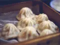 Pyszne, parujące dim sum w bambusowym koszyku. Delikatne pierożki kuszą swoim wyglądem.