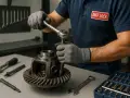 Mechanik w rękawiczkach dokręca śrubę w dyfrze. Na stole narzędzia i skrzynka z nasadkami.