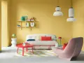 Ein Wohnzimmer mit gelben Wänden und einer auffälligen farb kombination aus Rot, Rosa und Weiß. Ein flauschiges Sofa und ein Sessel laden zum Entspannen ein.