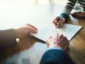Manos firmando un contrato de alquiler de piso. Los padres avalan el alquiler.