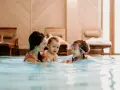 Rodzina cieszy się basenem w hotelu dla dzieci w Wiśle. Mama z dwójką dzieci pluska się w wodzie, tworząc radosne wspomnienia.