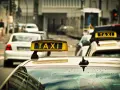 Ein Taxi mit leuchtendem "TAXI"-Schild auf dem Dach, bereit für Fahrten, auch im nachttarif. Regentropfen auf der Windschutzscheibe.